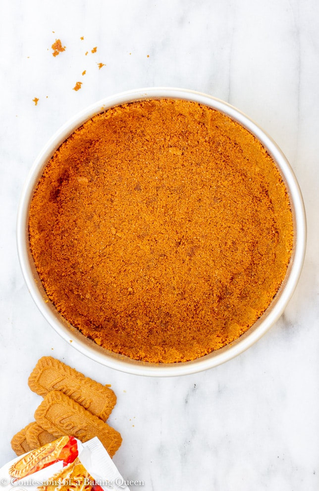 biscoff crust in a metal pan on a white marble surface