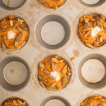 pumpkin cheesecake muffins topped with pumpkin seeds before baking