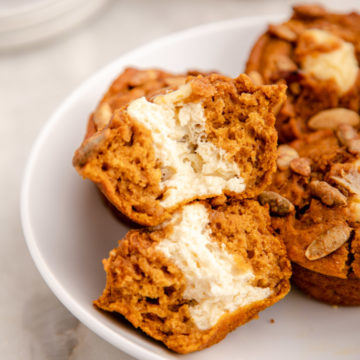 split in half cream cheese pumpkin muffin in a white bowl