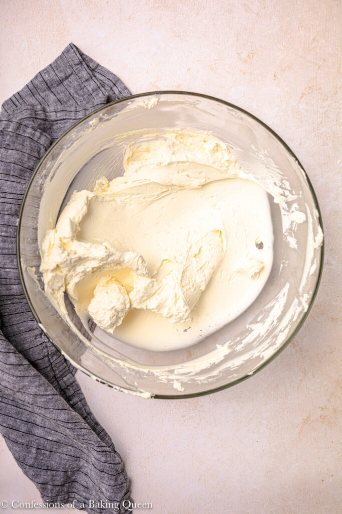 cream cheese mixed together until light and fluffy in a glass bowl on an light pink surface with a blue linen