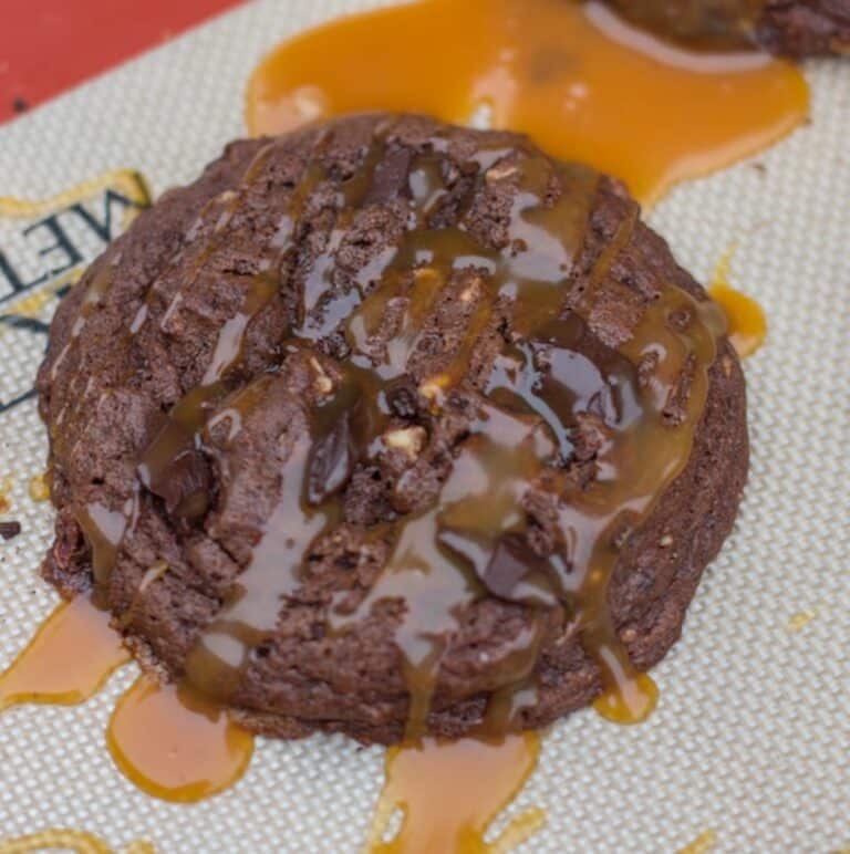 turtle cookies drizzled with caramel on a silpat lined baking sheet
