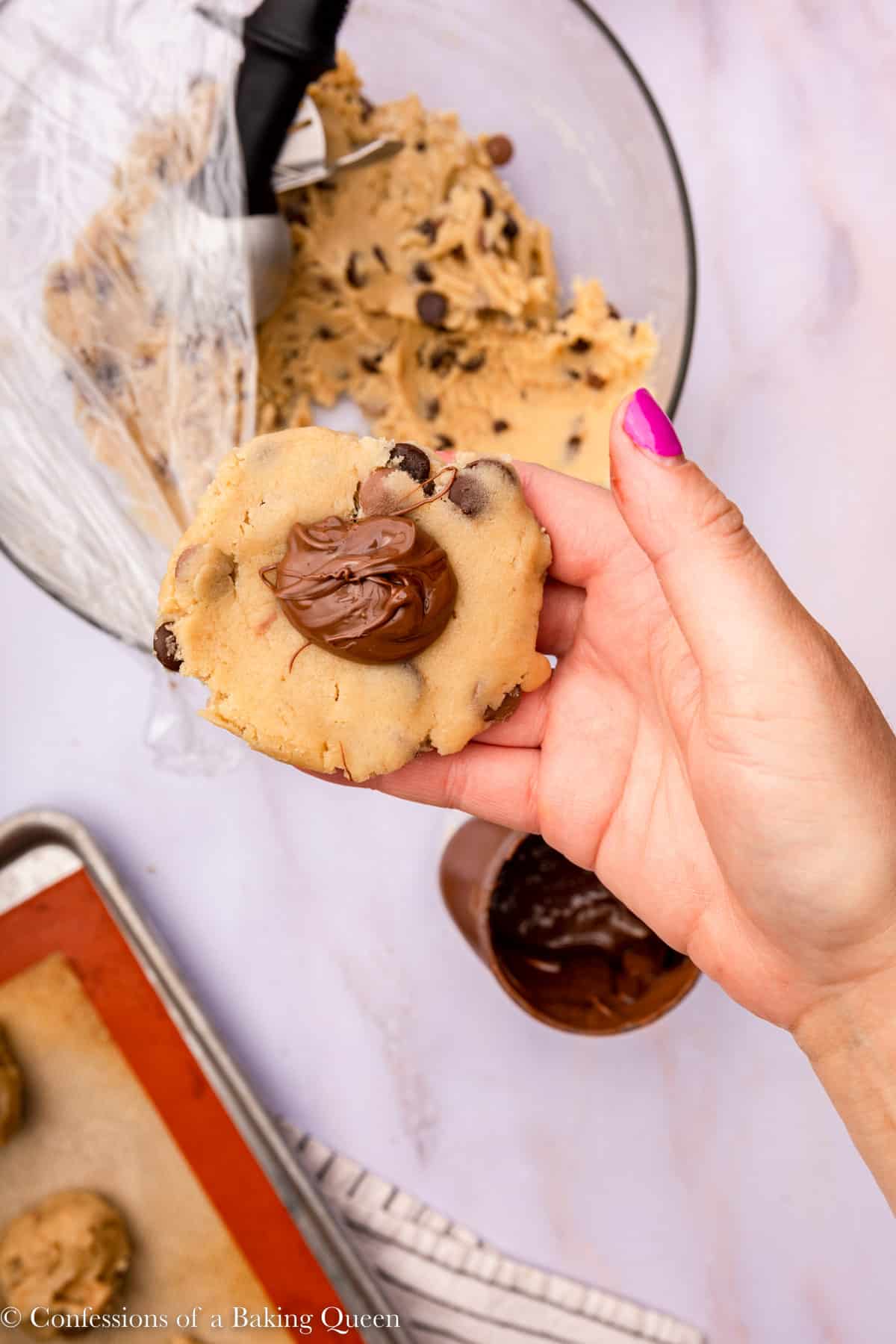 scoop of nutella added to cookie dough held up to the camera