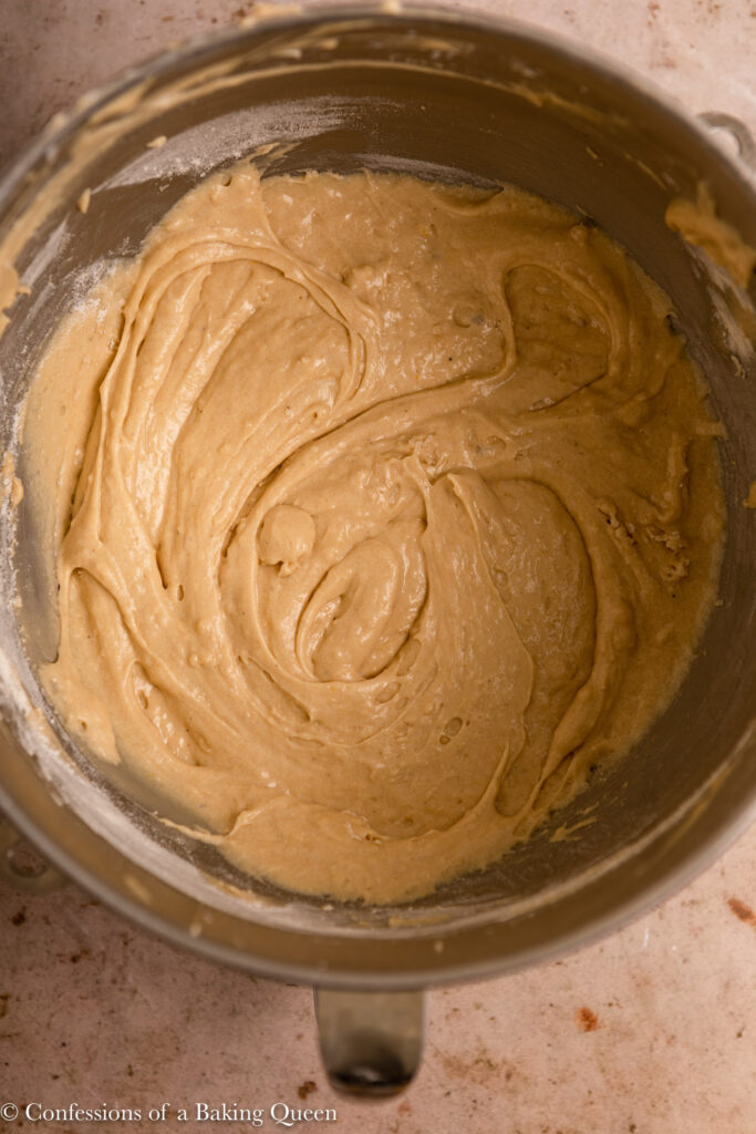 cream cheese pound cake batter in a metal mixing bowl on a light brown surface