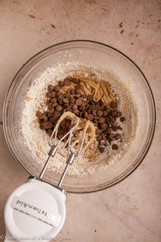 chocolate chips added to cookie dough with a handheld mixer