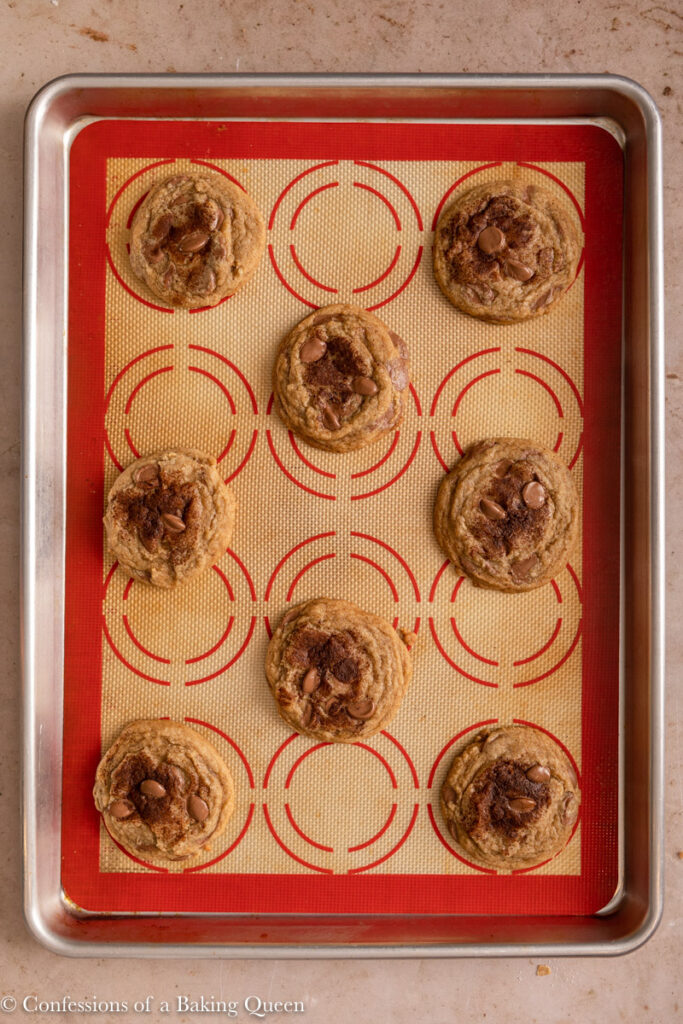 espresso chocolate chip cookies on a silpat. lined baking sheet on a light brown surface