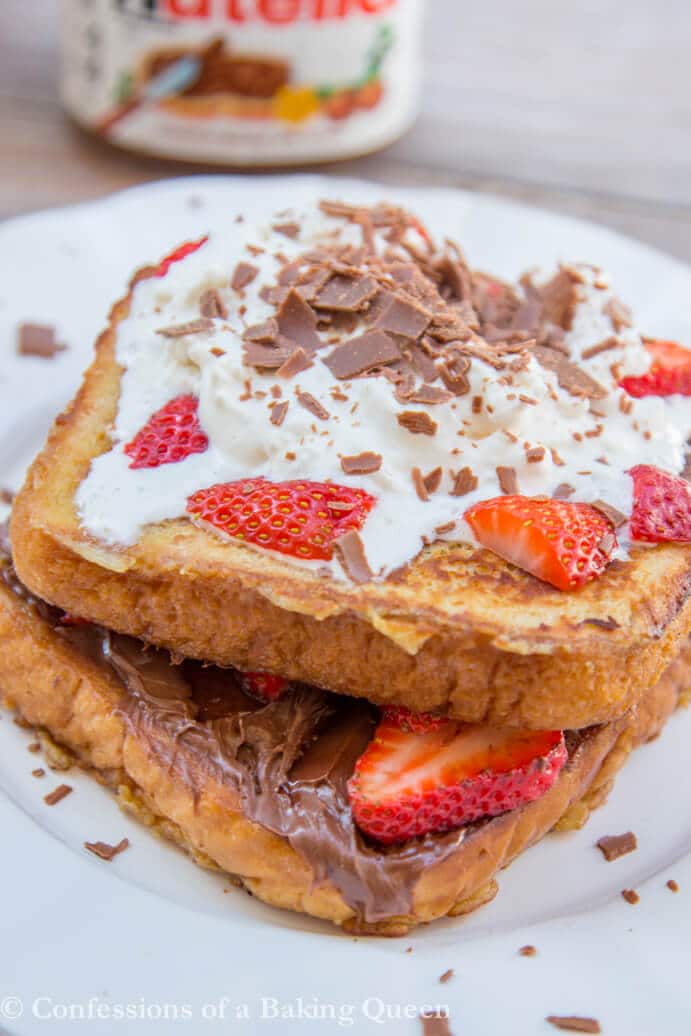 Nutella Strawberry French Toast on a white plate on a wood surface