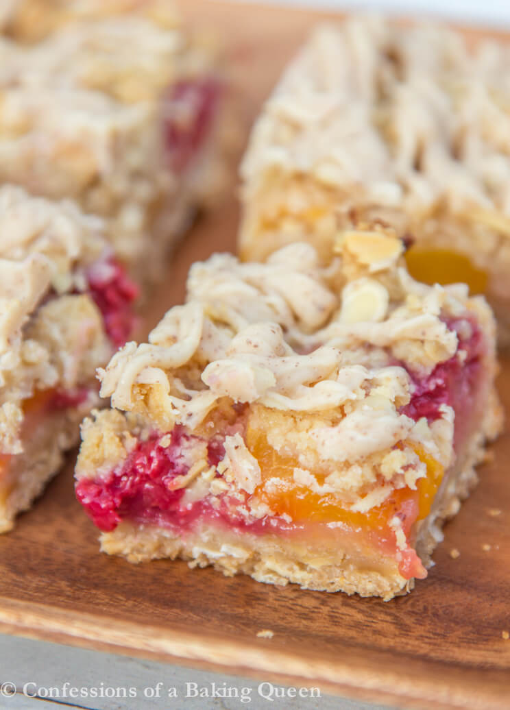 Peach Raspberry Crumble Bars close up on a wood plate on a white surface