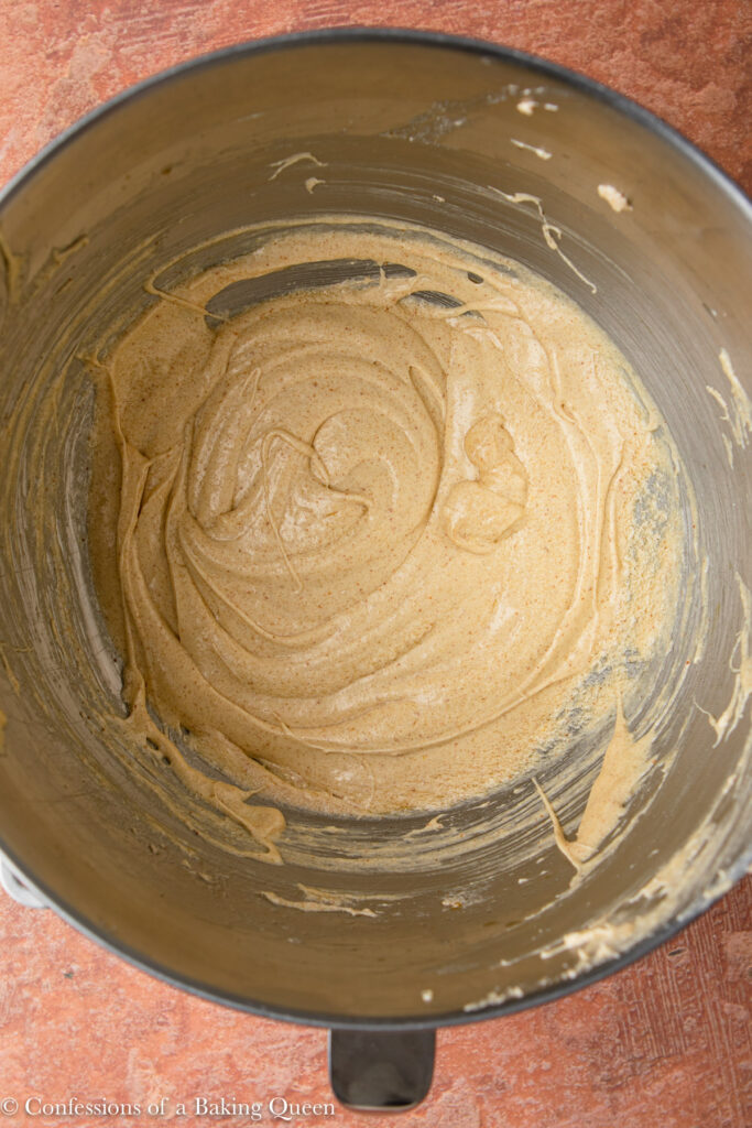 wet ingredients for a pumpkin cake recipe in a metal bowl on a reddish brown surface