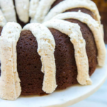 Guinness gingerbread cake with brown butter frosting served on a marble cake stand with a white and brown background