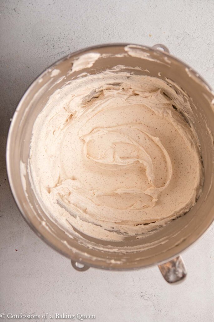 brown butter frosting whipped together in a metal bowl on a light grey surface