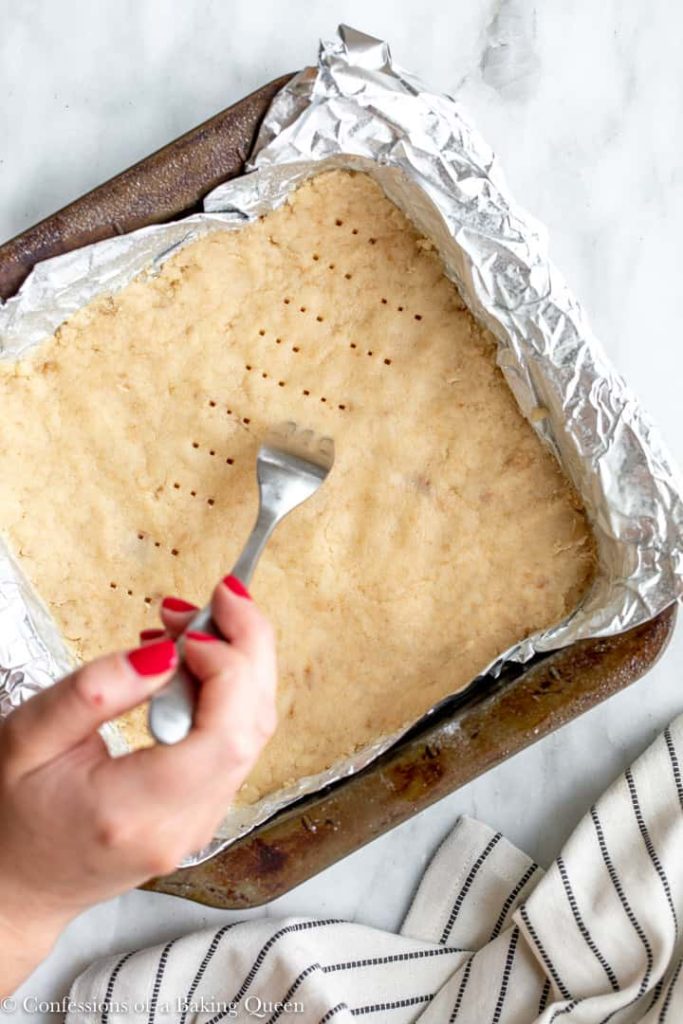 hand holding a fork to prick a shortbread crust