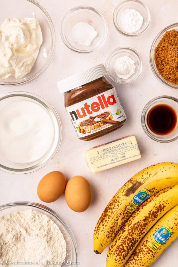 banana nutella muffin ingredients laid out on a light pink surface