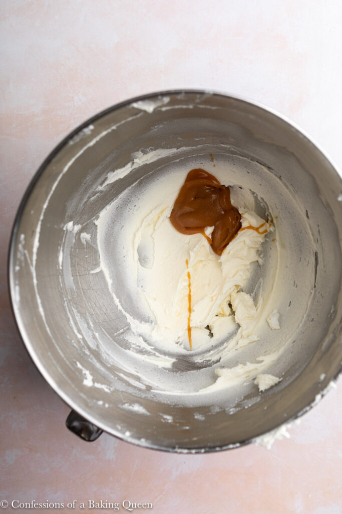 salted caramel added to creamed butter and sugar mixture in a metal bowl on a light pink surface