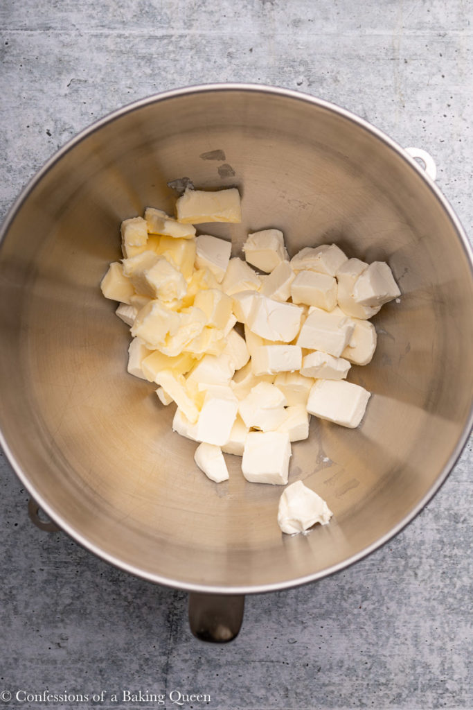 butter and cream cheese pieces in a metal mixing bowl  on a grey background