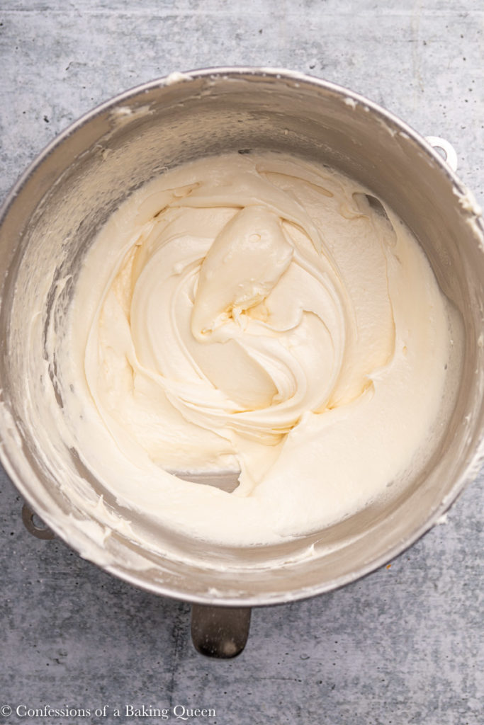 cream cheese frosting in a metal mixing bowl  on a grey background