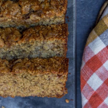 Oat Flour Skinny Banana Bread on a dark surface next to an orange and white checkered linen