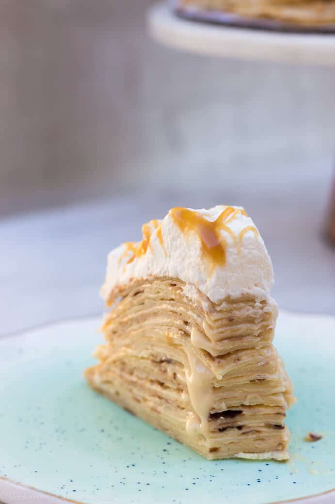 salted caramel crepe cake slice showing all the layers on a blue plate on a white background