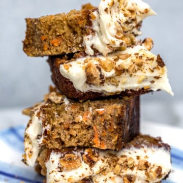 carrot pineapple banana loaf cake pieces stacked on top of each other on a blue and white plate on a grey background