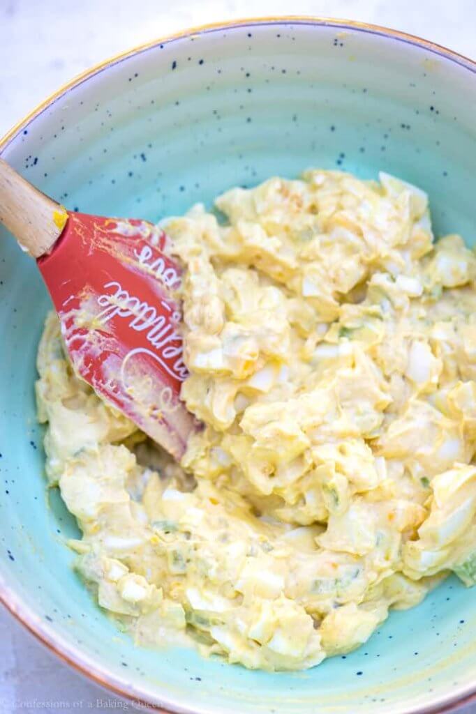 egg salad in a green bowl with an orange spatula