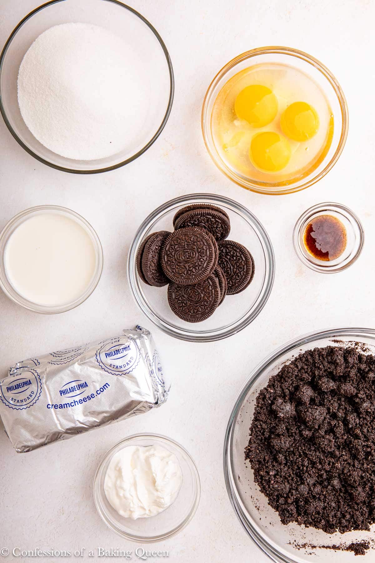 ingredients for mini oreo cheesecakes in small bowls on a light surface