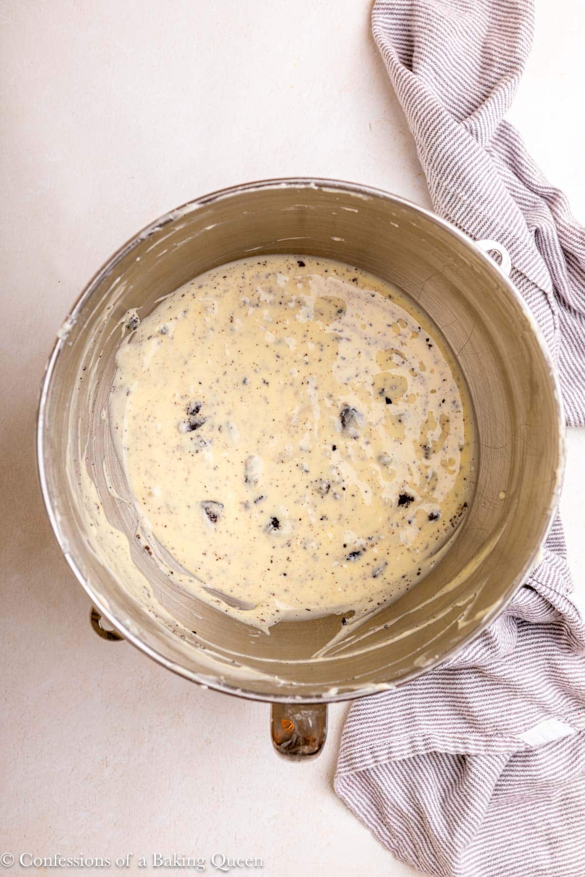 oreo cheesecake batter in a metal bowl on a light surface with a blue linen