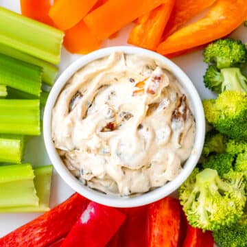 french onion dip in the center of the plate with fresh cut peppers, broccoli and celery