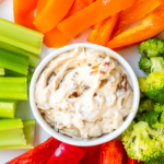 french onion dip serve in a white bowl with fresh cut veggies on a large white plate