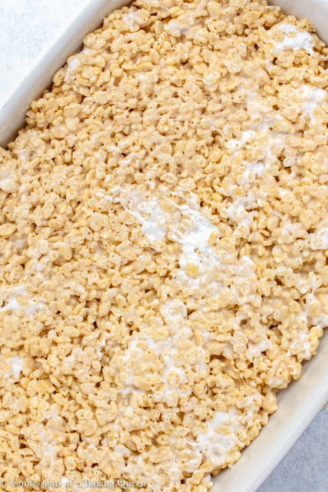 brown butter rice krispies pressed down into a white pan on a white background