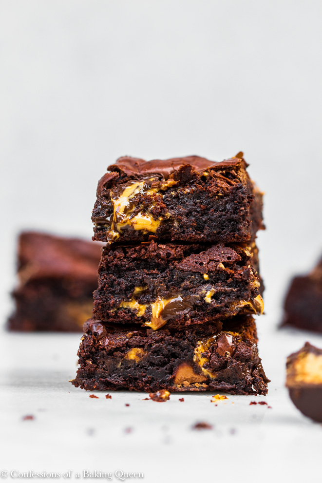peanut butter cup brownies stacked on top of each other on white marble surface