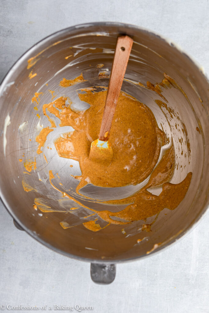 pumpkin cheesecake batter in a metal mixing bowl on a grey surface