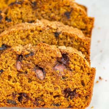 slices of chocolate chunk pumpkin bread on a white marble surface