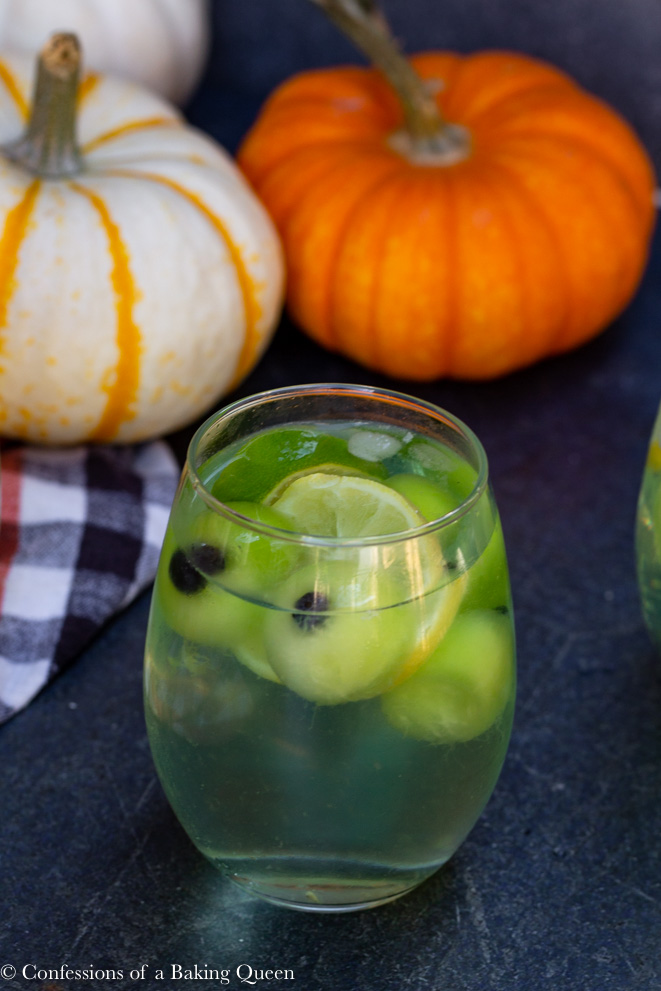 eyeball rum punch in a clear glass on a dark surface with pumpkins in the background