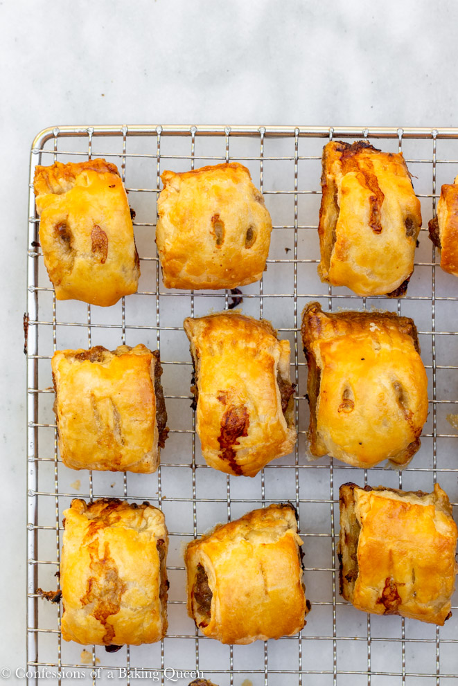 mini sausage rolls cooling on a wire rack on a white marble surface