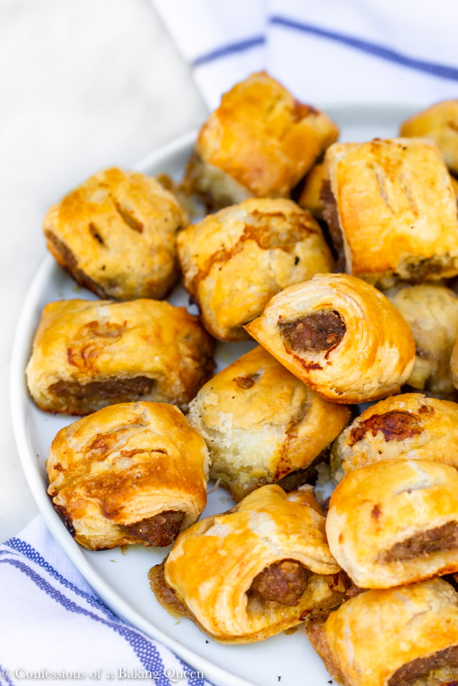sausage rolls recipe served on a white plate on top of white and blue tea towel