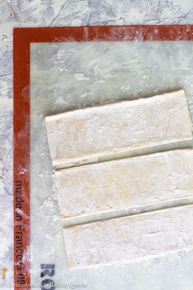 puff pastry sheets cut into thirds on a silpat workface on a grey background