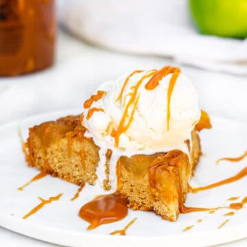 slice of upside down caramel apple cake on a white plate with ice cream and caramel drizzle