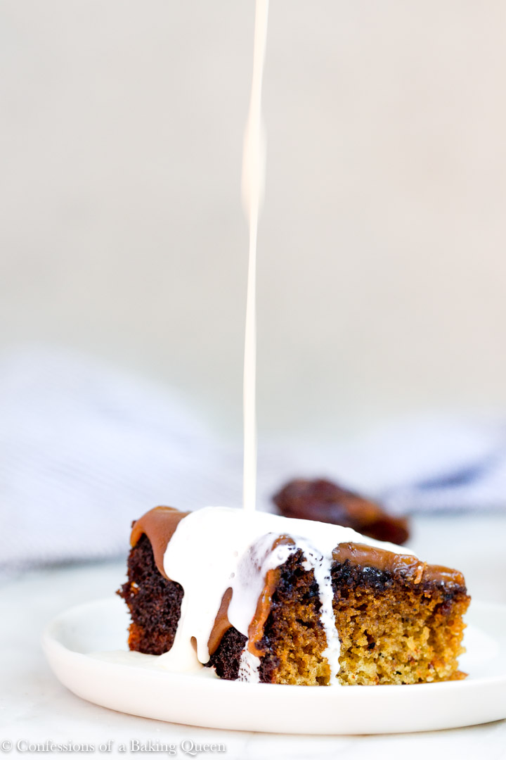 heavy cream pouring on a slice of sticky toffee pudding recipe on a white plate
