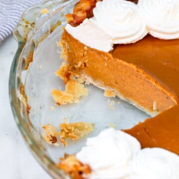 pumpkin pie in a glass pie dish with a slice missing