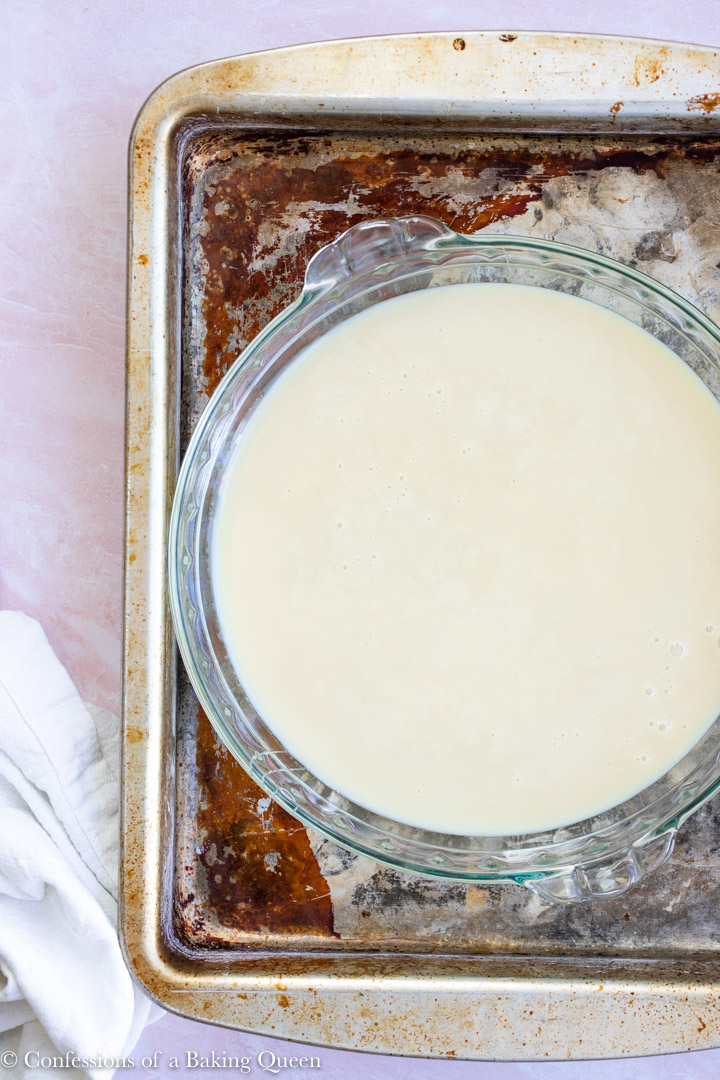 sweetened condensed milk in a round pie dish in a roasting pan for a banoffee pie recipe