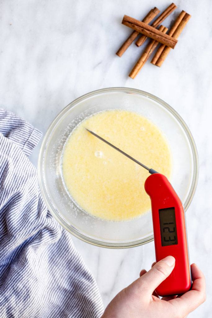 thermometer in a glass bowl of milk and butter for a brown butter cinnamon roll recipe