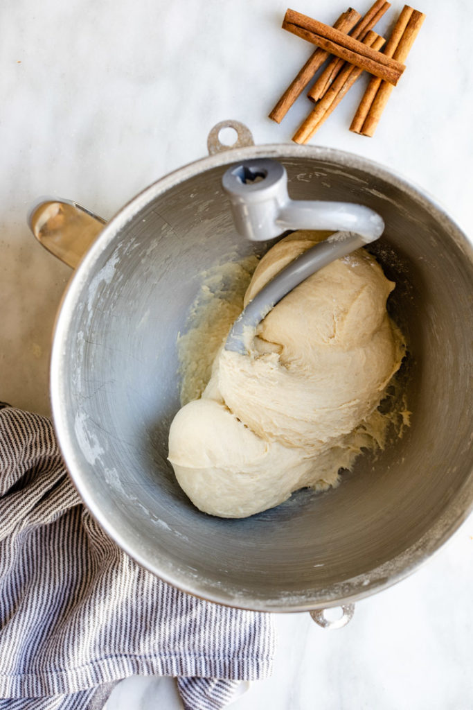 brown butter cinnamon roll dough in a metal mixing bow with a dough hook