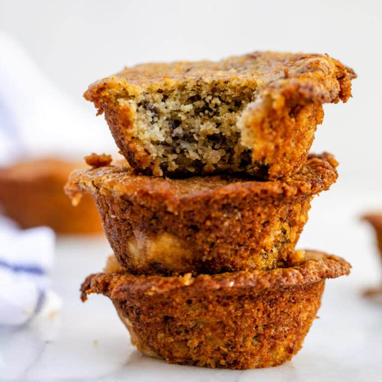 oat flour banana bread muffins stacked on top of each other on a white marble surface