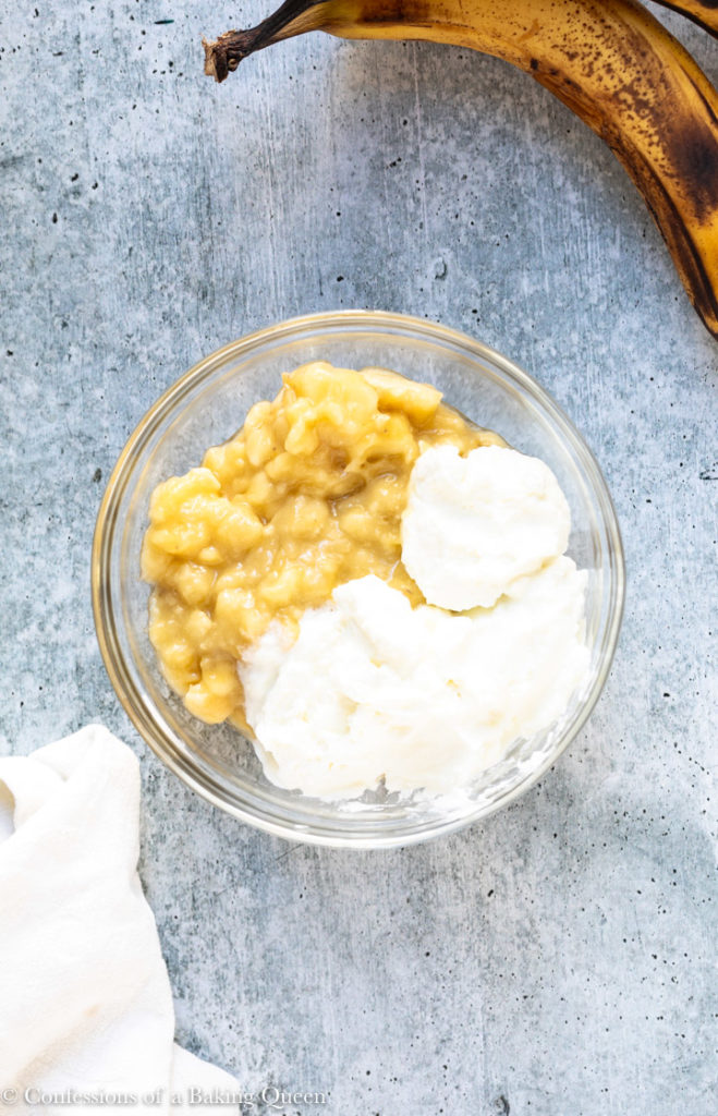 mashed bananas and sour cream in a glass bowl for a chocolate swirl banana bread recipe