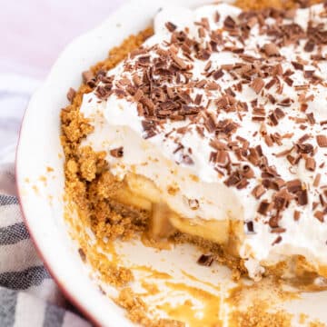 banoffee pie in a ceramic pie dish with a slice missing