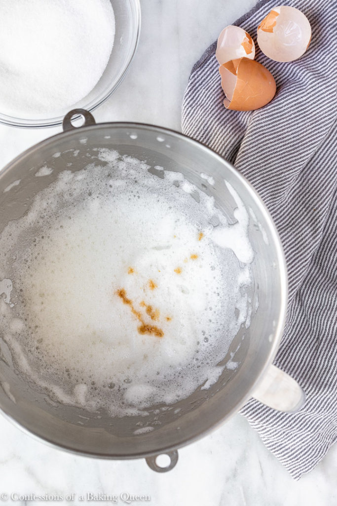 vanilla extract added to meringue in a metal mixing bowl
