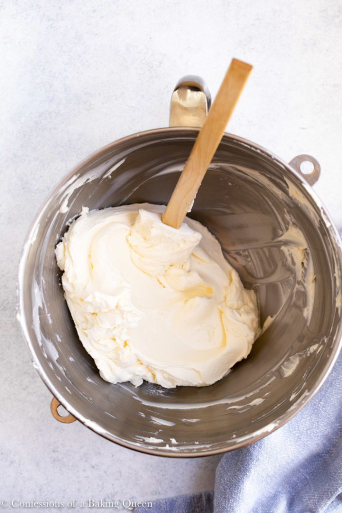 cream cheese in a metal mixing bowl with a spatula 