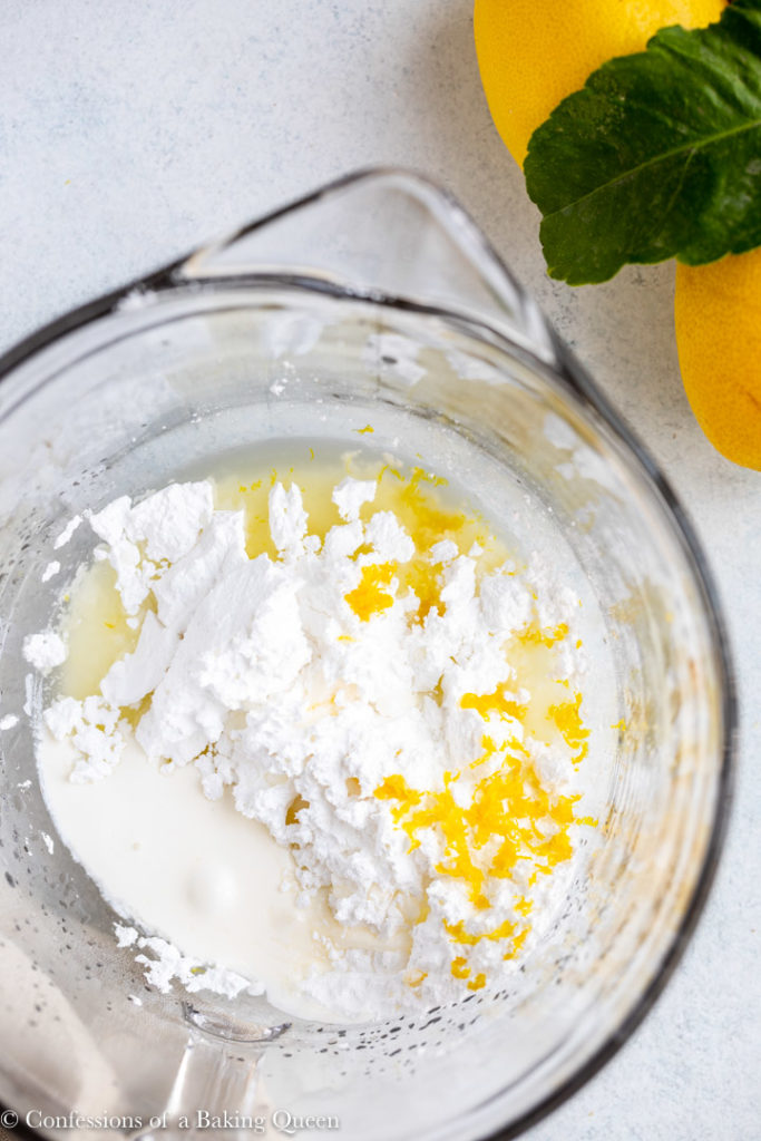 large glass mixing bowl with powdered sugar, lemon zest, lemon juice, and heavy cream