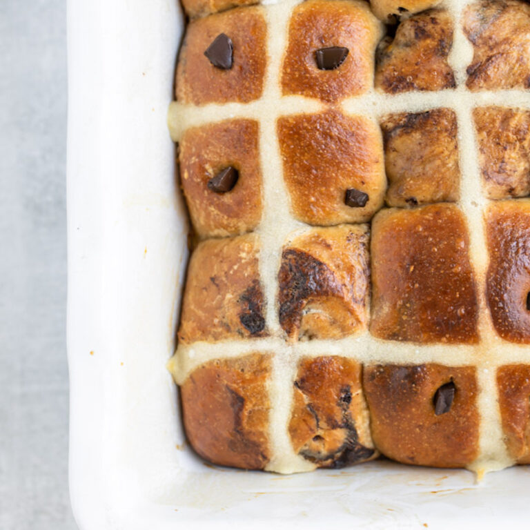 close up of chocolate hot cross buns in a rectangle ceramic dish