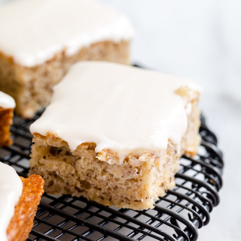 banana bars with cream cheese frosting on top of a black rack