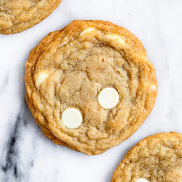 three white chocolate cookies on a marble surface